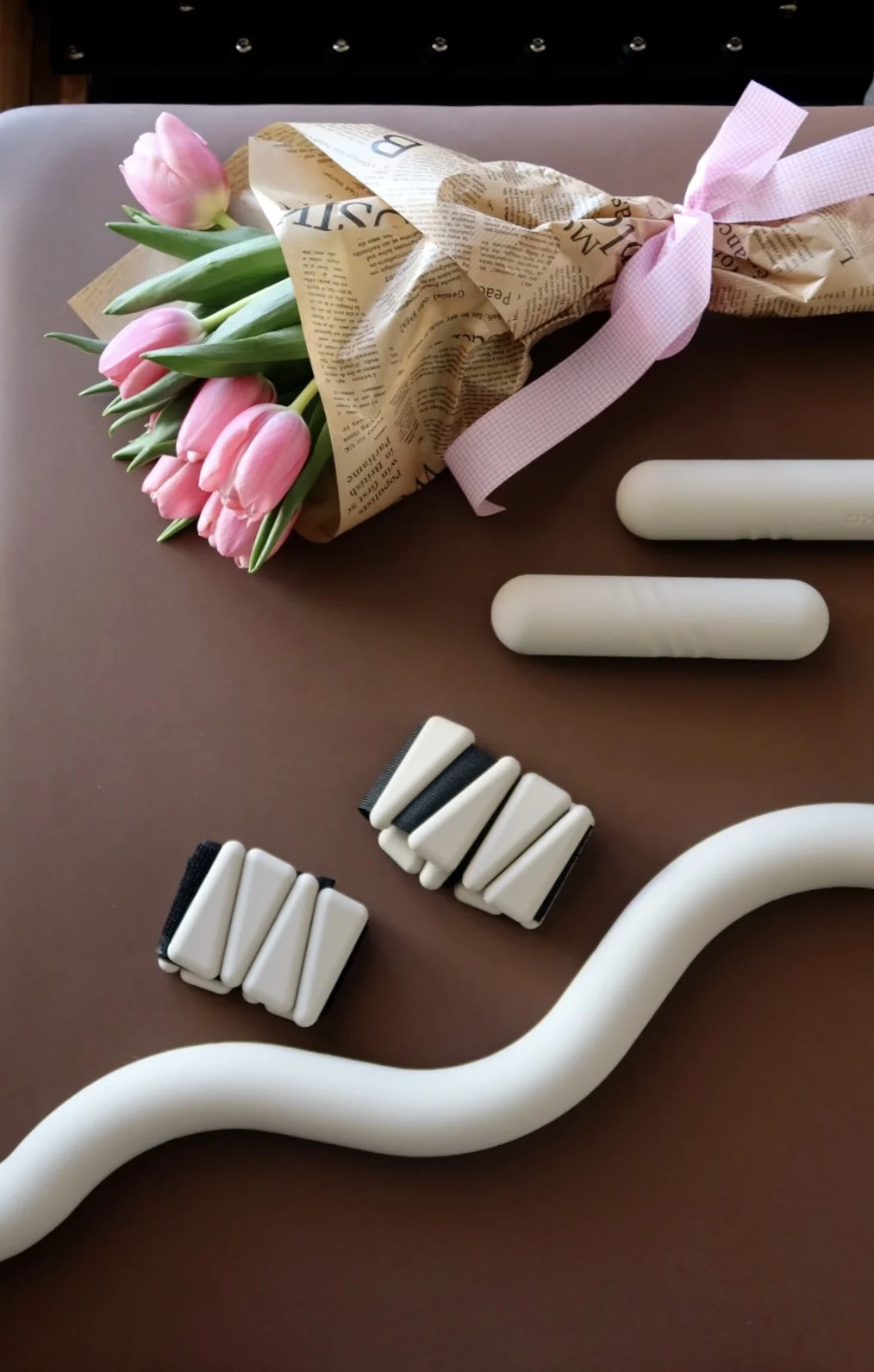 Pilates props and tulips arranged on a brown reformer